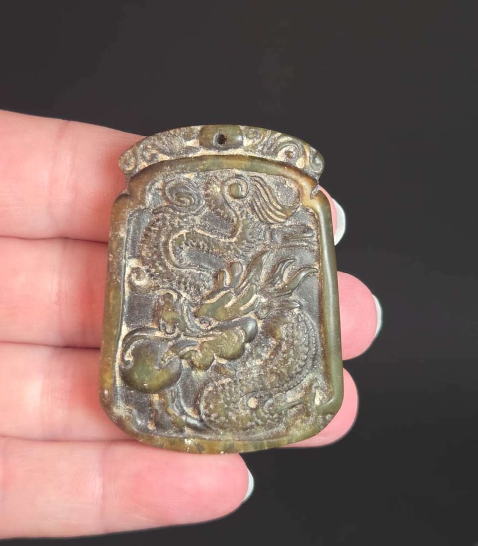 vintage or antique Asian Jade amulet: likely Chinese Jade or other stone pendant or large amulet depicting a full body Dragon holding a ball, in mottled green and brown tones aprox. 2" long by 1 1/2" wide