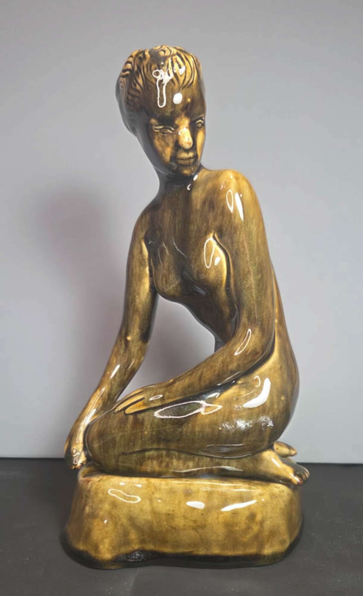 Thai vintage pottery nude statue: Mid Century Modern vintage greenish brown pottery 2-part nude female statue of a kneeling woman looking behind her and sitting on a (separate piece) stone, by a company in Thailand, marked