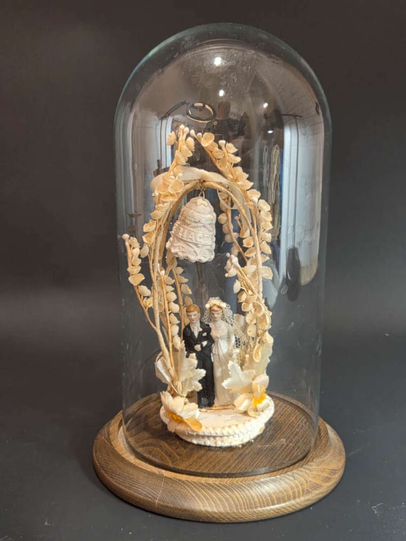 vintage wedding cake topper: vintage wooden base with glass dome and underneath a 1930's fabric, pressed heavy cardstock wedding cake topper with bride and groom, bell with Marriage written on it and floral or