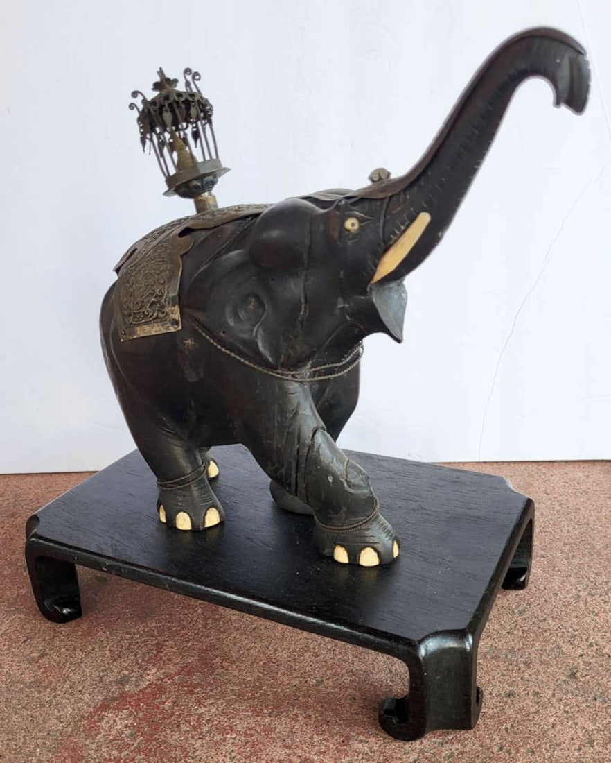 antique carved wooden East Asian figural elephant statue: likely made in India this is an antique carved (Ebony?) wooden sculpture of an elephant with his trunk up, carved bone tusks and nails on his feet and silver or brass repousse ear adornments and
