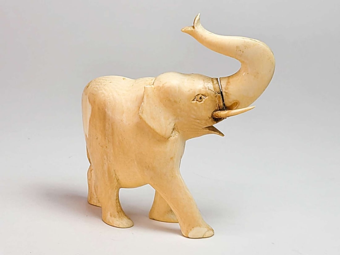 antique bone figural animal statue: small carved bone figurine of an elephant with upturned trunk, made in 2 parts and with attached tusks (one partially missing), no maker's mark aprox. 3" long by 3 1/4" high