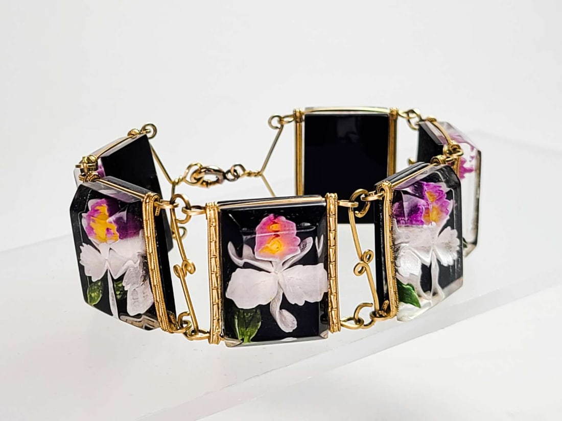vintage estate jewelry: Lucite bracelet: vintage gold toned wire bracelet with black background carved Lucite floral or Orchid flower vibrantly colored designs inside about 7 1/4" in length