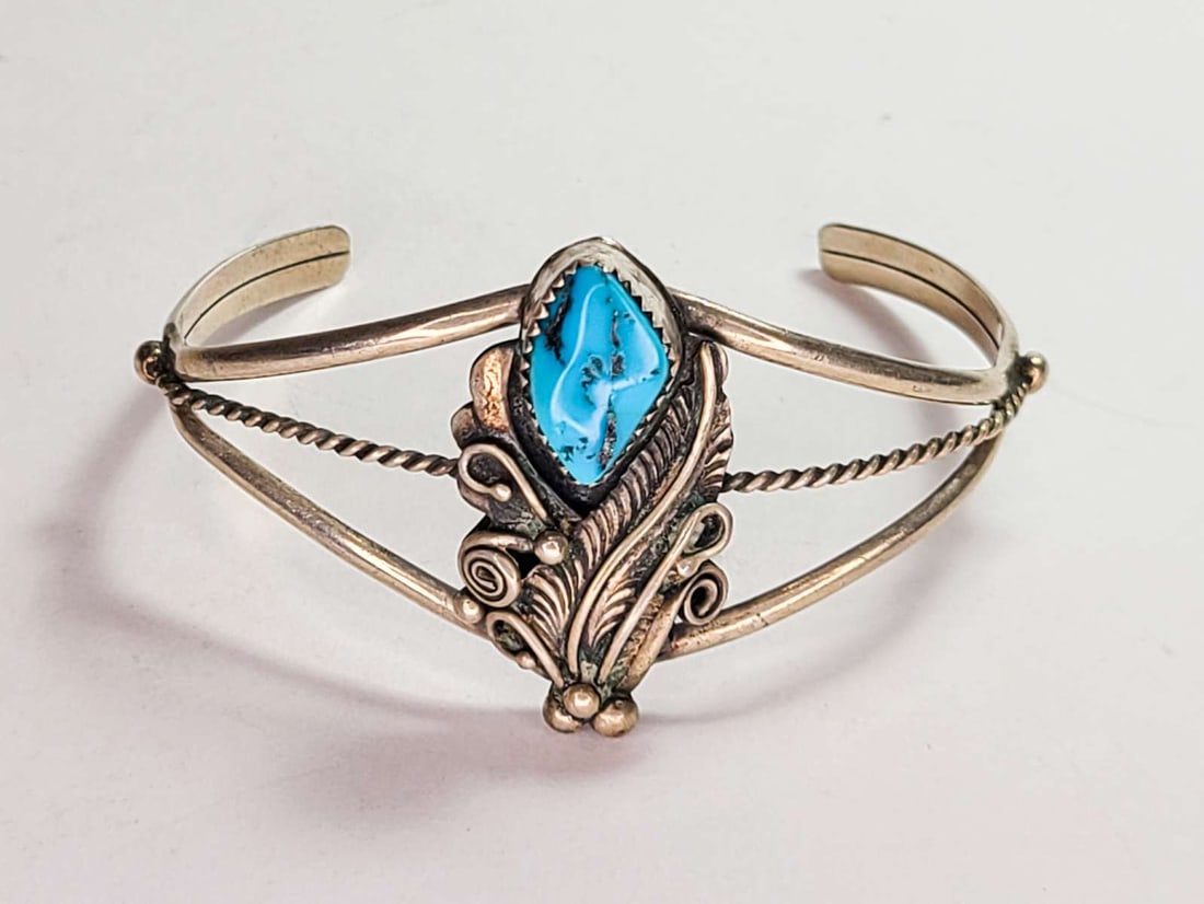 vintage estate jewelry: Native American bracelet: vintage Native American Indian cuff bracelet with mark for Sterling silver and artist's sign, rope design with typical Southwest motifs of feathers and central Turquoise nugget stone centra