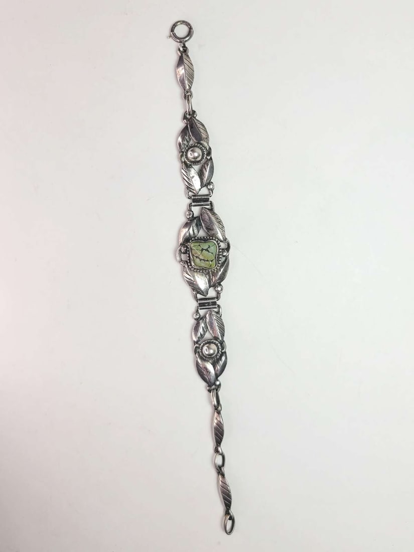 vintage estate jewelry: Native American bracelet: vintage Native American Indian bracelet with mark for Sterling silver, with typical Southwest motifs of feathers and design with central green Turquoise polished nugget stone about 6 1/2" l