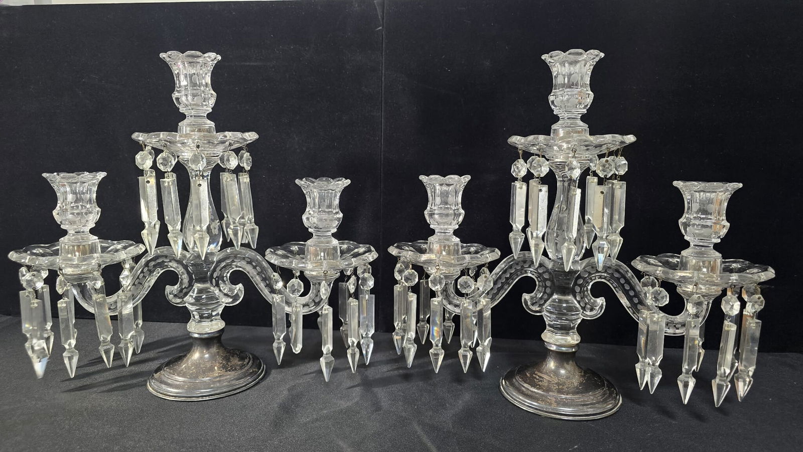 Pair of Antique Crystal Girandole Candelabras with Sterling base: Beautiful pair of 2-arm crystal girandole candelabras featuring hand-cut crystal bobeches, scalloped candle cups with frosted dot decoration, and multiple tiers of faceted crystal prisms.Each candelab