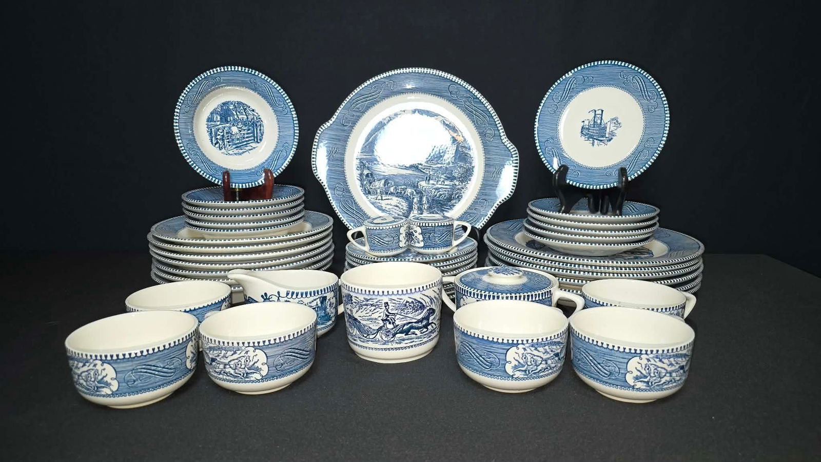 Vintage Royal Currier & Ives “The Rocky Mountains” Blue Transferware Dinnerware Set: Vintage Royal Currier & Ives dinnerware set in the “The Rocky Mountains” pattern, featuring classic blue transferware scenes depicting historic American landscapes, transportation, and frontie