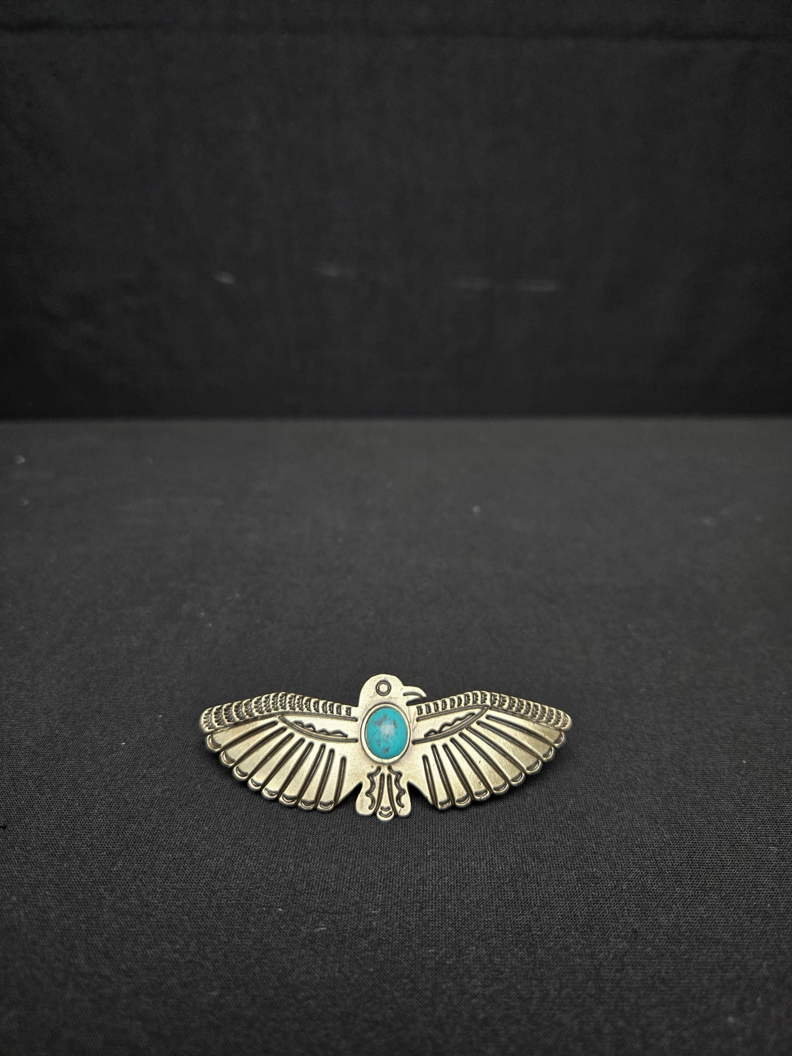 Vintage Navajo Style Thunderbird Pin with Turquoise Inlay: Vintage Navajo style pin associated with the Fred Harvey era, featuring a turquoise stone and stamped detailing.