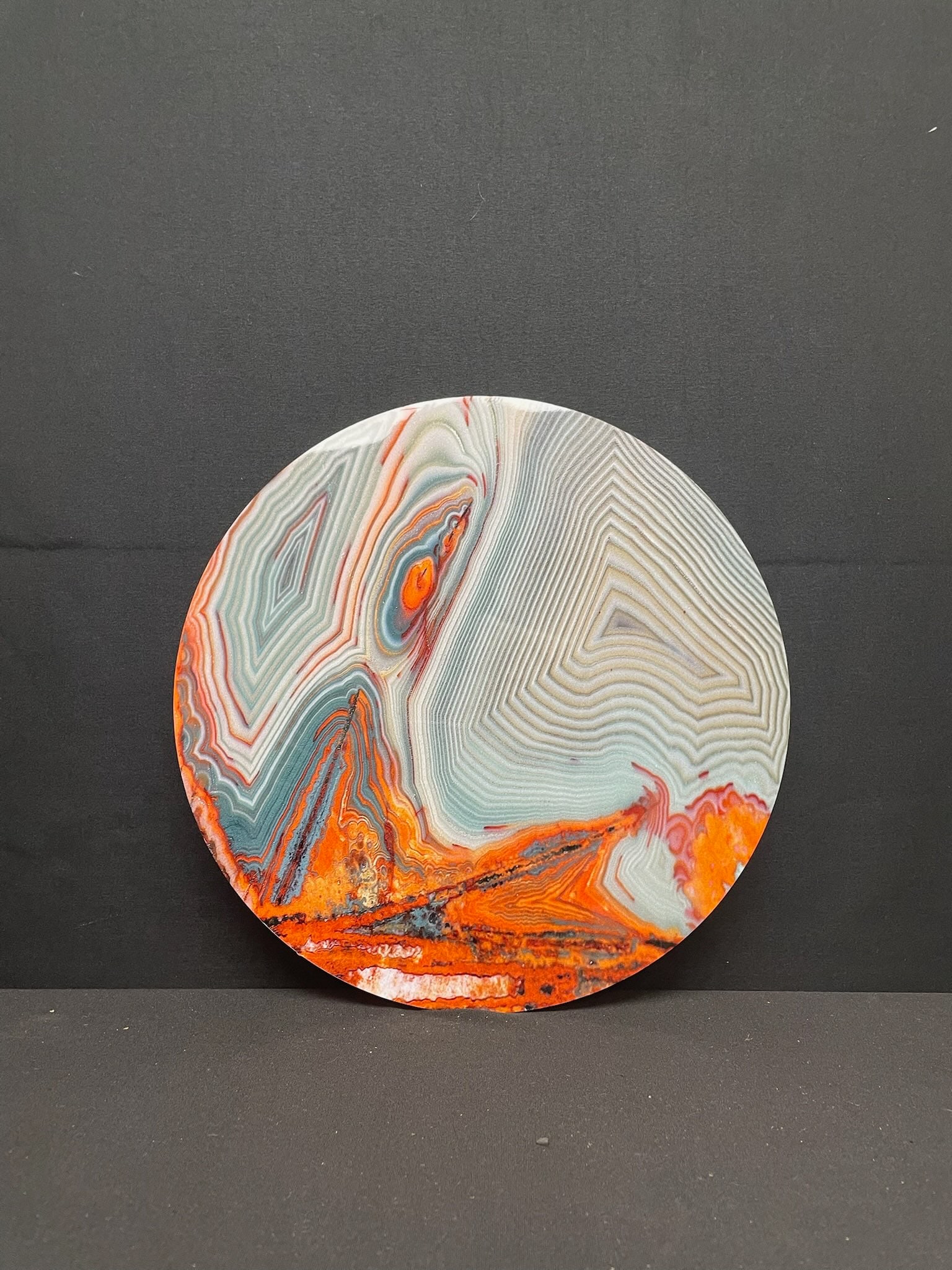 Round Metal Paint Pour Art Lake Superior: Round metal disk featuring a paint pour depiction of Lake Superior in warm and cool tones, the back featuring a raised metal square frame for display/hanging purposes.