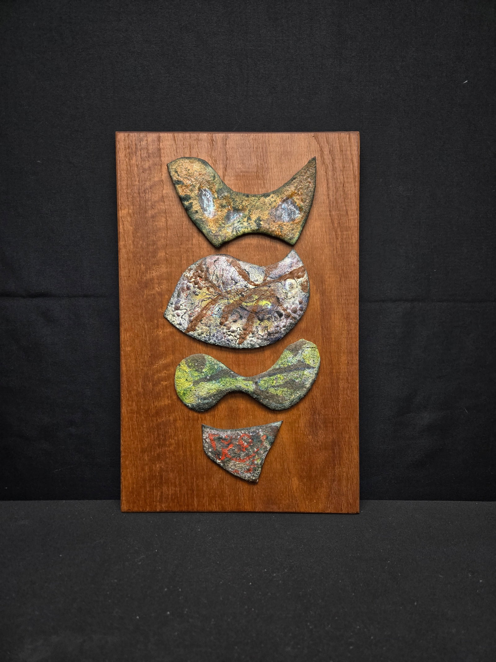 Abstract Painted Stone Wall Hang on Wood: Abstract hand painted stones mimicking the shape of a fish, mounted on a wood board with wire backing for display.