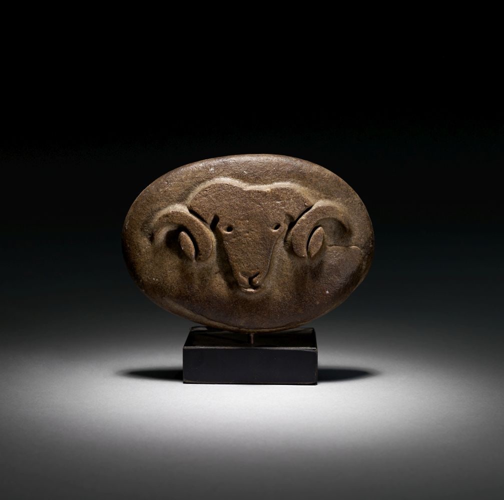 A MESOPOTAMIAN GRANITE CARVED RAM PLAQUE, EARLY DYNASTIC, CIRCA 2550-2250 B.C. (1 of 3)