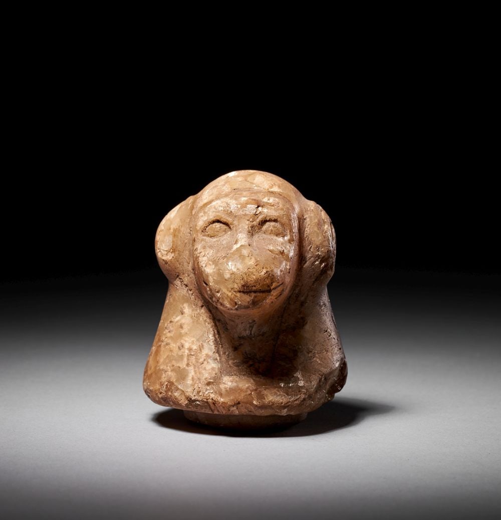 AN EGYPTIAN ALABASTER LID IN THE FORM OF A BABOON, NEW KINGDOM TO LATE PERIOD, CIRCA 1550-525 B.C.: Lot 3. AN EGYPTIAN ALABASTER LID IN THE FORM OF A BABOON New Kingdom to Late Period, Circa 1550–525 B.C. Carved from translucent, warm beige calcite alabaster, this lid is sculpted in the round