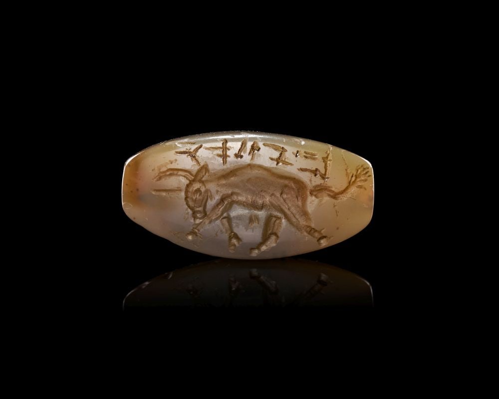 A LATE MINOAN CHALCEDONY AMYGDALOID SEAL DEPICTING A BULL, CIRCA 1450-1300 B.C.: A LATE MINOAN CHALCEDONY AMYGDALOID SEAL DEPICTING A BULL, CIRCA 1450-1300 B.C.Finely carved from a lustrous chalcedony of milky translucence, this elegant amygdaloid seal embodies the refined glyptic