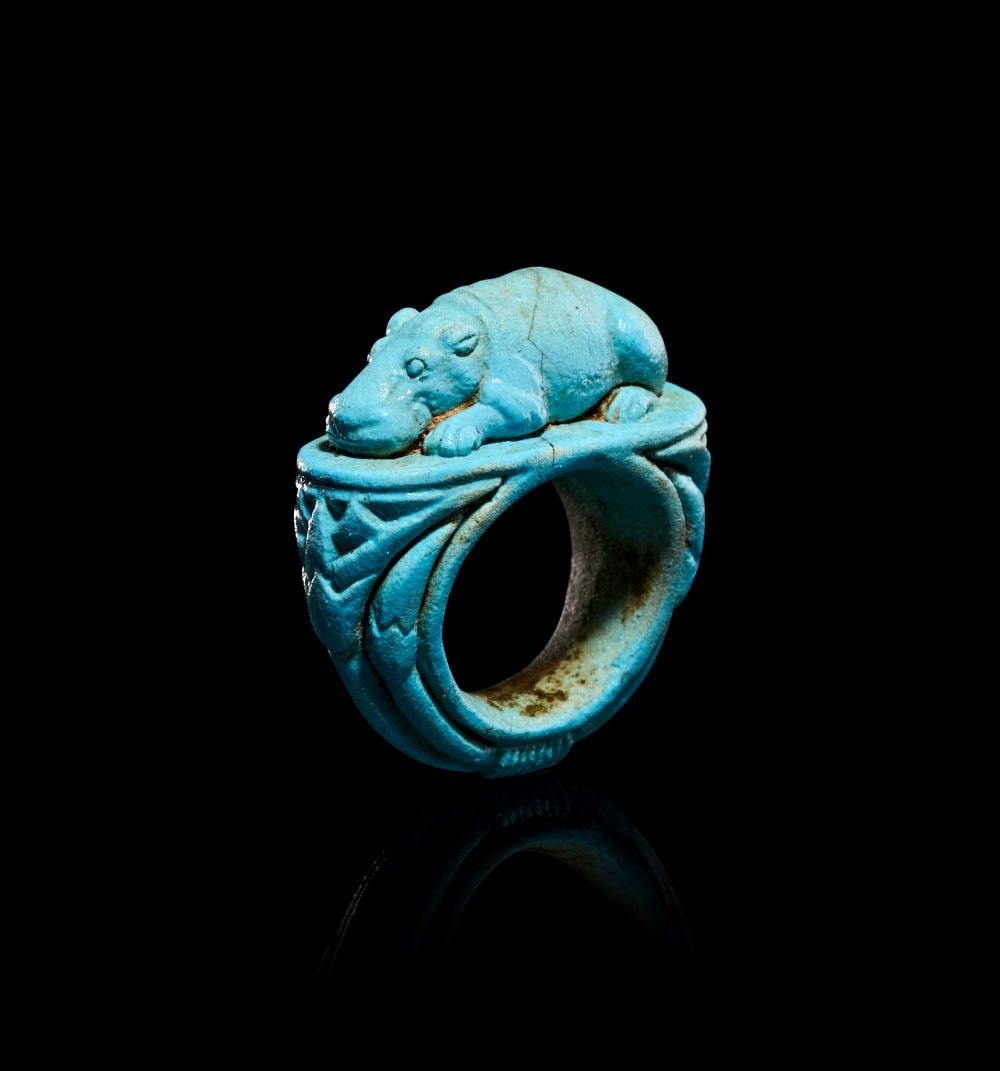 AN EGYPTIAN FAIENCE HIPPOPOTAMUS RING, NEW KINGDOM, DYNASTY XVIII, 1550-1307 B.C.: AN EGYPTIAN FAIENCE HIPPOPOTAMUS RING, NEW KINGDOM, DYNASTY XVIII, 1550–1307 B.C. Modelled in vivid turquoise faience, this charming ring is formed as a robust hoop surmounted by a miniature h