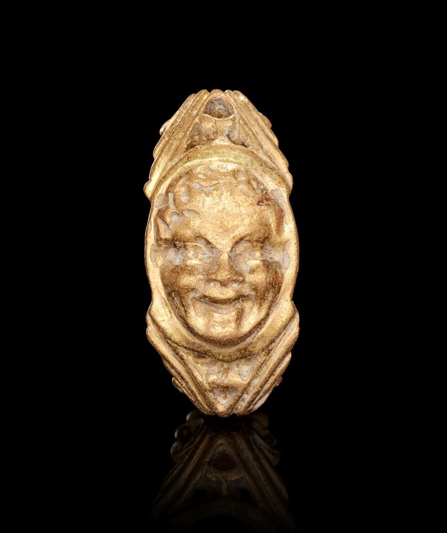A ROMAN GOLD RING DEPICTING A SATIRICAL FACE, CIRCA 1ST-2ND CENTURY A.D.: A ROMAN GOLD RING DEPICTING A SATIRICAL FACE, CIRCA 1ST–2ND CENTURY A.D. Finely cast in warm-toned gold, this striking Roman ring is set with an oval bezel carved in relief with a lively satir