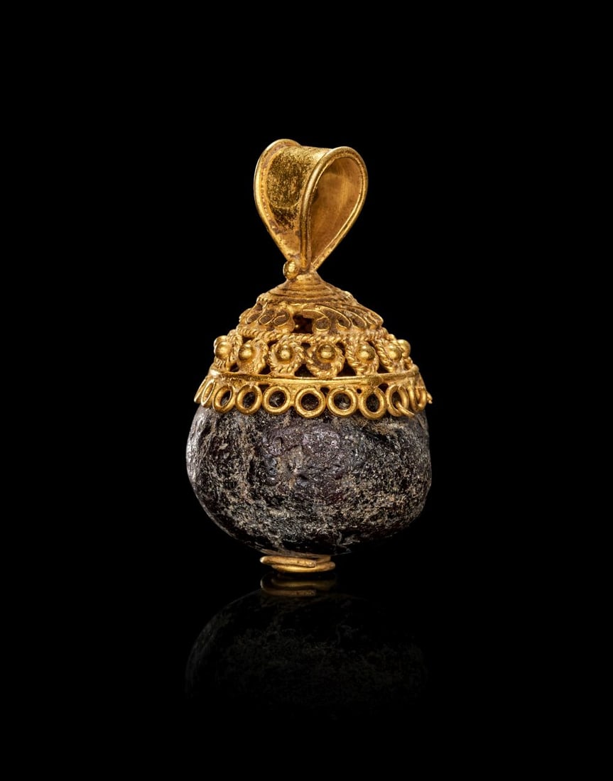 A ROMAN GOLD & GARNET AMULET, CIRCA 1ST-2ND CENTURY A.D.: A ROMAN GOLD & GARNET AMULET, CIRCA 1ST–2ND CENTURY A.D. Finely fashioned in rich, warm-toned gold, this Roman amulet is centred upon a substantial spherical garnet of deep wine-red hue, i