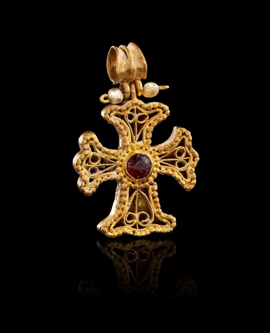 A BYZANTINE GOLD AND GARNET PENDANT CROSS CIRCA 6TH CENTURY A.D.: A BYZANTINE GOLD AND GARNET PENDANT CROSS, CIRCA 6TH CENTURY A.D. Fashioned in high-carat gold, this finely-worked pendant cross presents a bold, softly swelling silhouette, its arms expanding towar