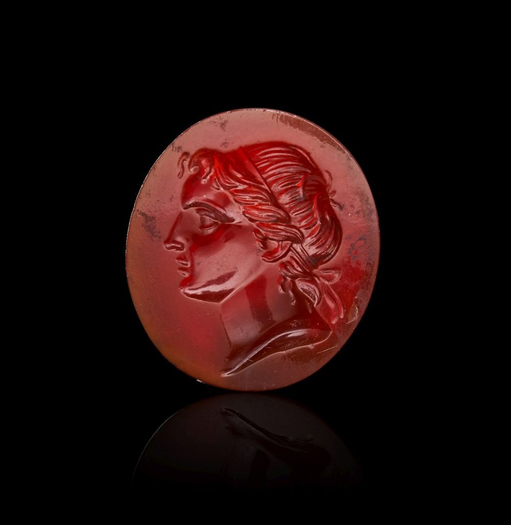 A ROMAN CARNELIAN CAMEO DEPICTING A YOUNG ALEXANDER THE GREAT, CIRCA 1ST-3RD CENTURY A.D.: A ROMAN CARNELIAN CAMEO DEPICTING A YOUNG ALEXANDER THE GREAT, CIRCA 1ST–3RD CENTURY A.D. Carved from a richly saturated carnelian of deep, glowing red, this finely worked Roman cameo presents