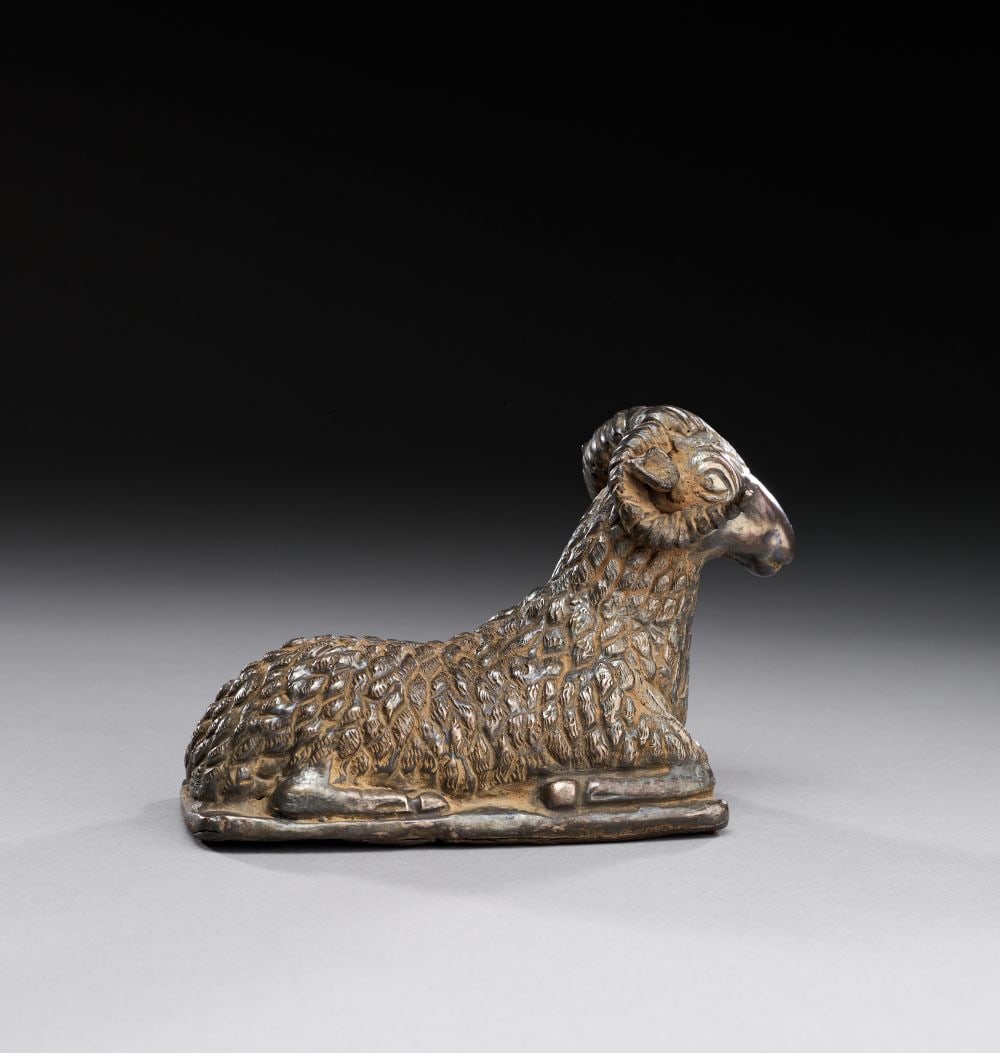 AN ACHAEMENID SILVER SEATED RAM, CIRCA 5TH-4TH CENTURY B.C.: AN ACHAEMENID SILVER SEATED RAM, CIRCA 5TH-4TH CENTURY B.C. A finely cast silver figure depicting a