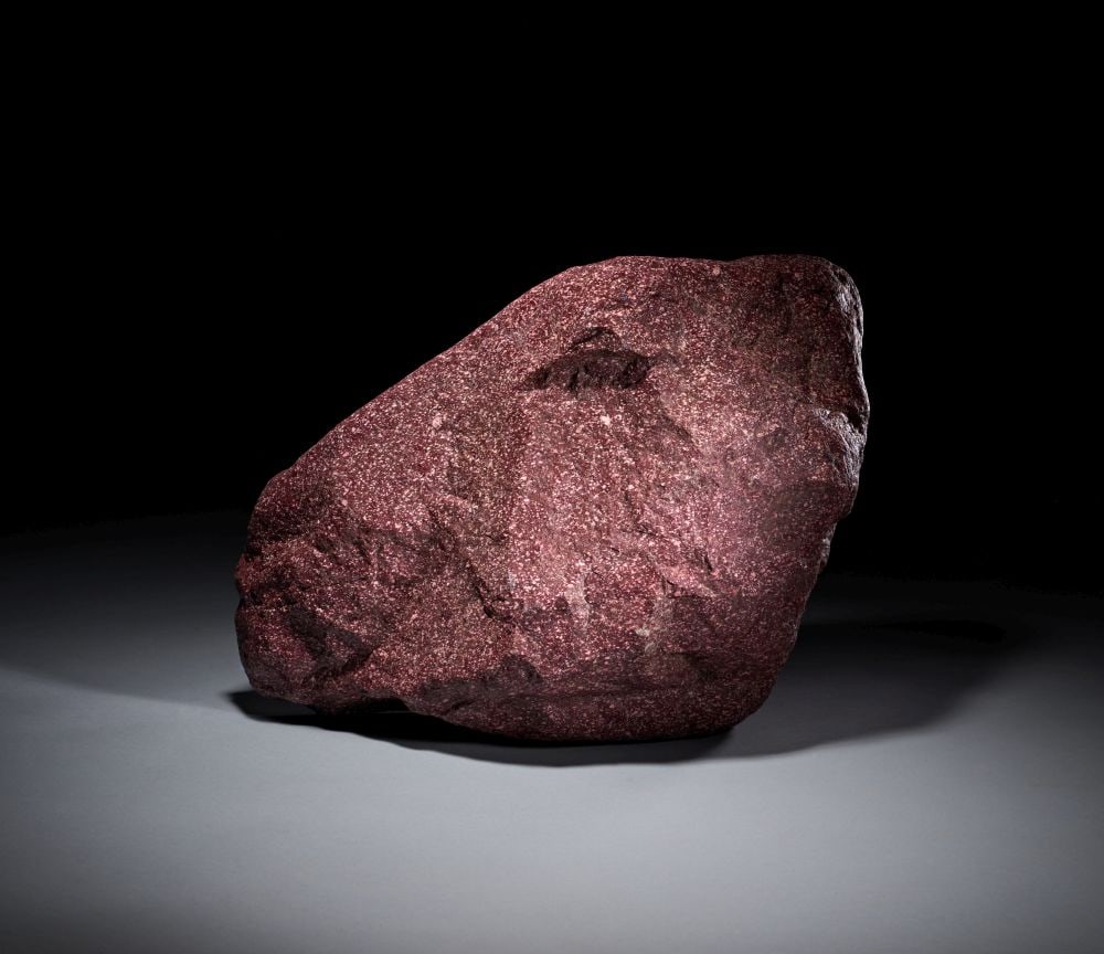 A MOUNMENTAL ITALIAN IMPERIAL PORPHYRY FRAGMENT LATE 18TH/EARLY 19TH CENTURY: A MONUMENTAL ITALIAN IMPERIAL PORPHYRY FRAGMENT, LATE 18TH–EARLY 19TH CENTURY Carved from richly hued imperial porphyry, this monumental fragment presents a powerful and elemental presence. It