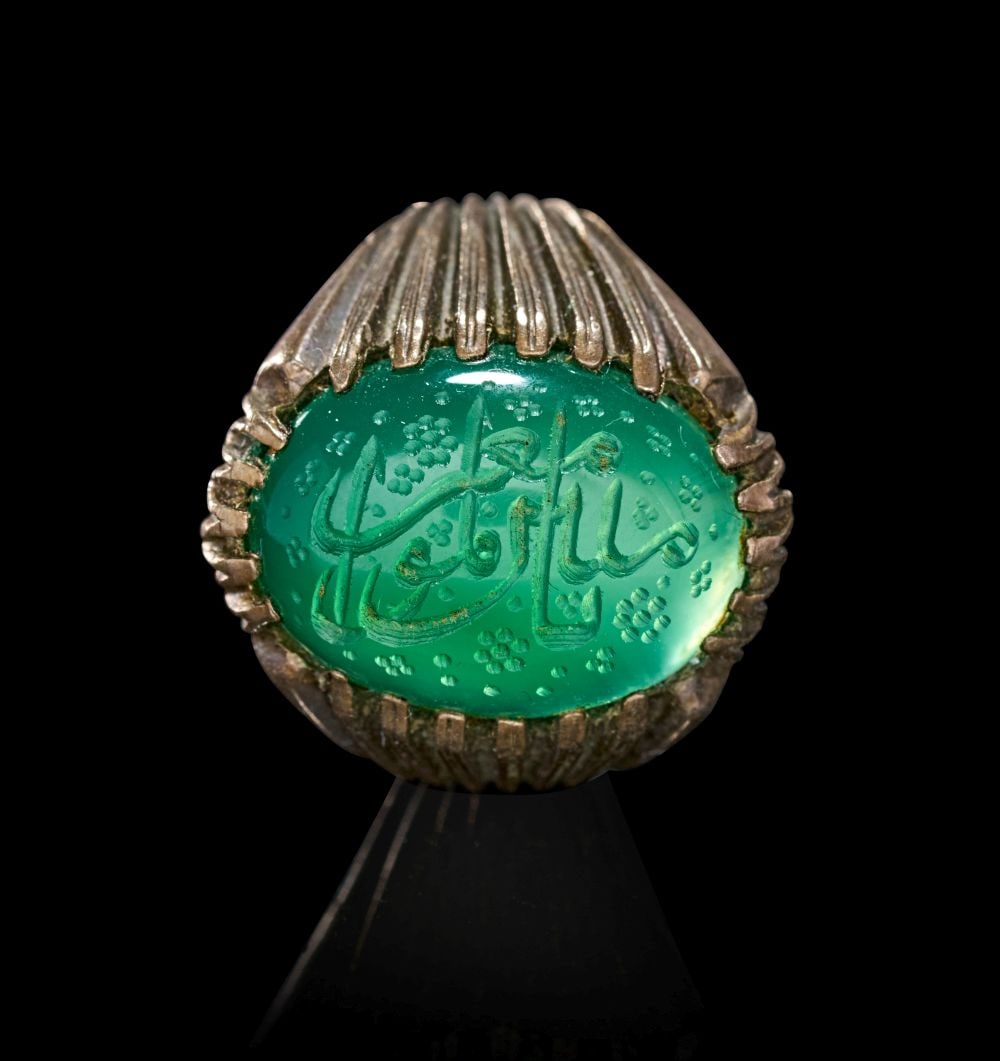 A CALLIGRAPHIC INSCRIBED EMERALD RING, 19TH CENTURY, PERSIA: A CALLIGRAPHIC INSCRIBED EMERALD RING, 19TH CENTURY, PERSIA This striking Persian ring centres on a substantial oval emerald, its rich translucent green surface finely engraved with flowing calligra