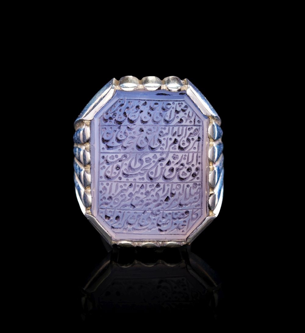 A CALLIGRAPHIC INSCRIBED AGATE RING, 19TH CENTURY, PERSIA: A CALLIGRAPHIC INSCRIBED AGATE RING, 19TH CENTURY, PERSIA This substantial 19th-century Persian ring is set with a pale lavender-grey agate, cut to an octagonal form and engraved across its flat sur