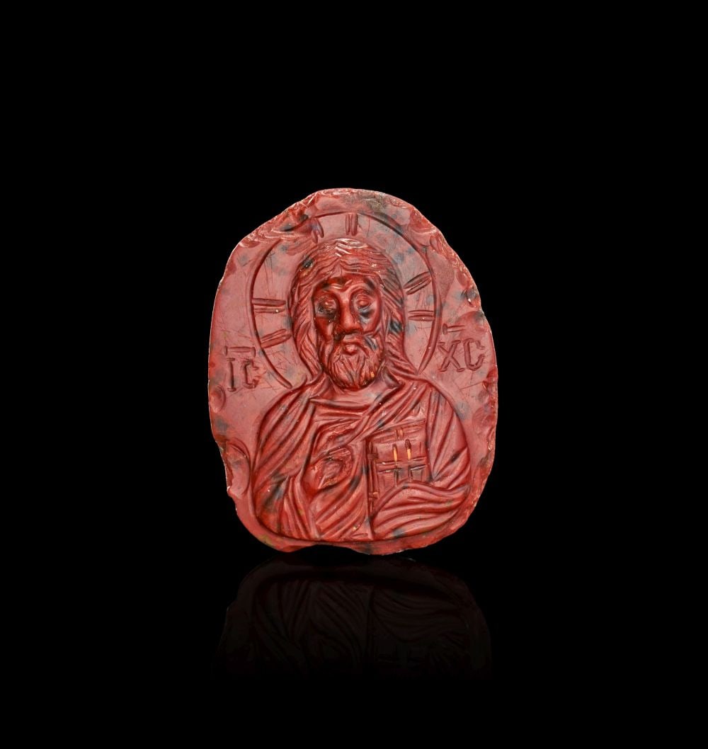 A CARVED JASPER CAMEO OF CHRIST PANTOKRATOR WITH CROSS REVERSE, 11TH-12TH CENTURY A.D.: A CARVED JASPER CAMEO OF CHRIST PANTOKRATOR WITH CROSS REVERSE, 11TH-12TH CENTURY A.D. Superbly executed oval cameo carved in richly mottled red and black jasper, presenting a striking frontal bust of