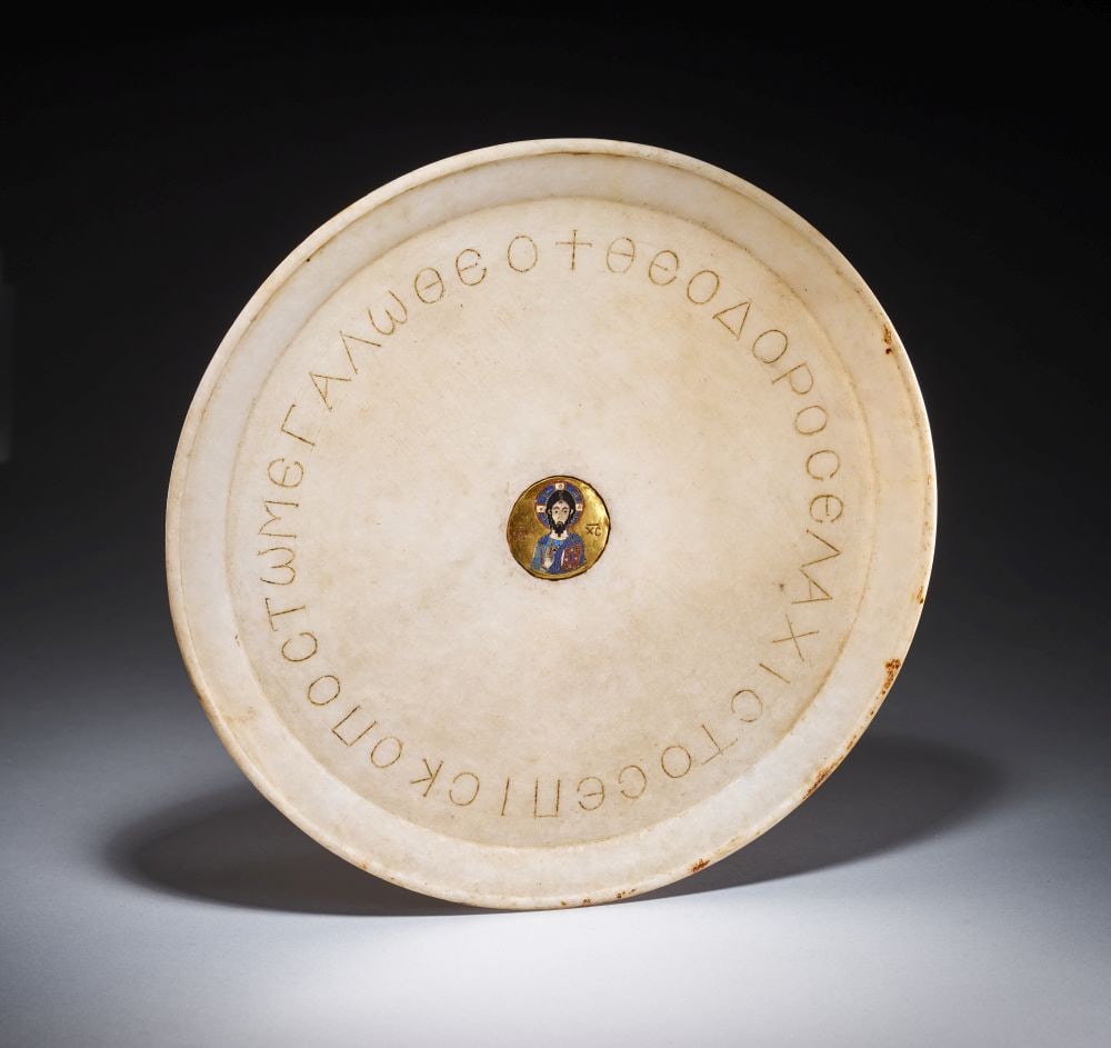 AN INSCRIBED BYZANTINE MARBLE DISC WITH A GOLD MEDALLION DEPICTING CHRIST, CIRCA 11TH CENTURY: AN INSCRIBED BYZANTINE MARBLE DISC WITH A GOLD MEDALLION DEPICTING CHRIST, CIRCA 11TH CENTURY Carved from pale marble, this Byzantine disc is of broad circular form, with a slightly raised rim and a s