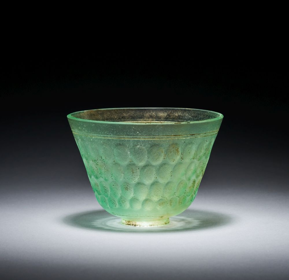 AN INTACT SASSANIAN GREEN CUT WHEEL CUT GLASS BOWL CIRCA 6TH-7TH CENTURY A.D.: AN INTACT SASSANIAN GREEN CUT WHEEL CUT GLASS BOWL CIRCA 6TH-7TH CENTURY A.D. An intact Sassanian green wheel-cut glass bowl, circa 6th–7th century A.D., of translucent pale green glass with a s