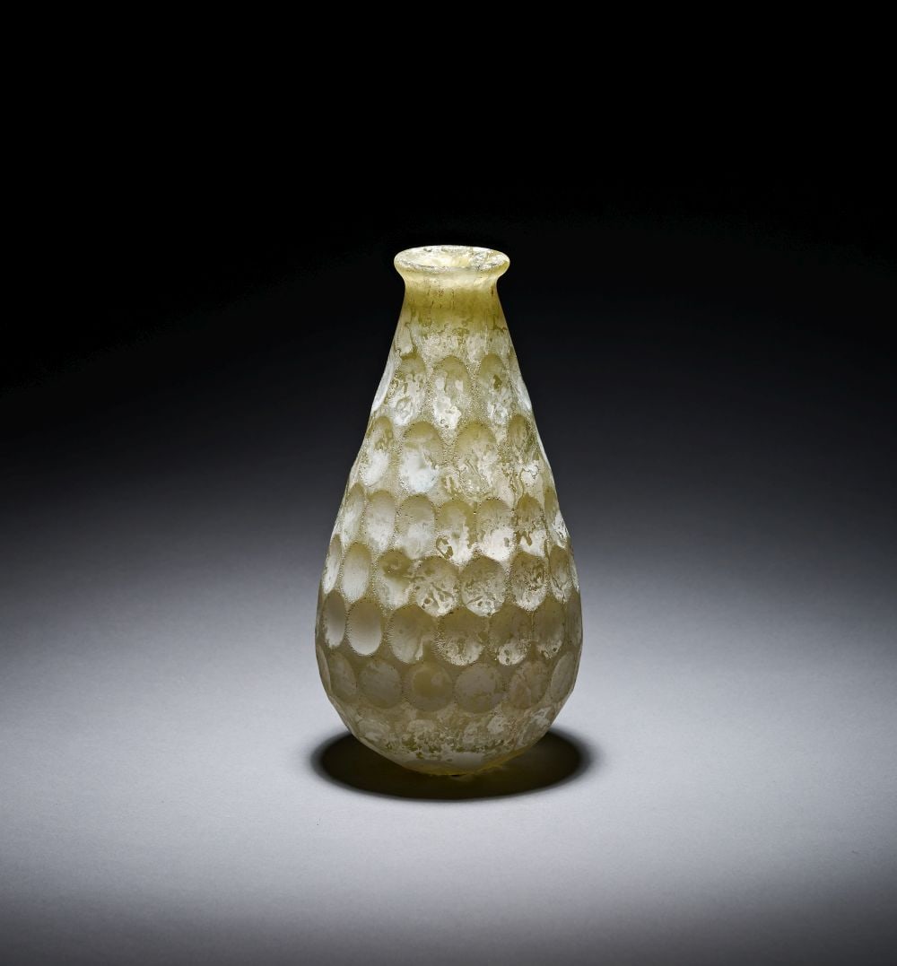 A SASANIAN FACET-CUT GREEN GLASS BOTTLE CIRCA 4TH-6TH CENTURY A.D.: A SASANIAN FACET-CUT GREEN GLASS BOTTLE CIRCA 4TH-6TH CENTURY A.D. A Sasanian facet-cut green glass bottle, circa 4th–6th century A.D., of elegant pear-shaped form with rounded lower body, taper