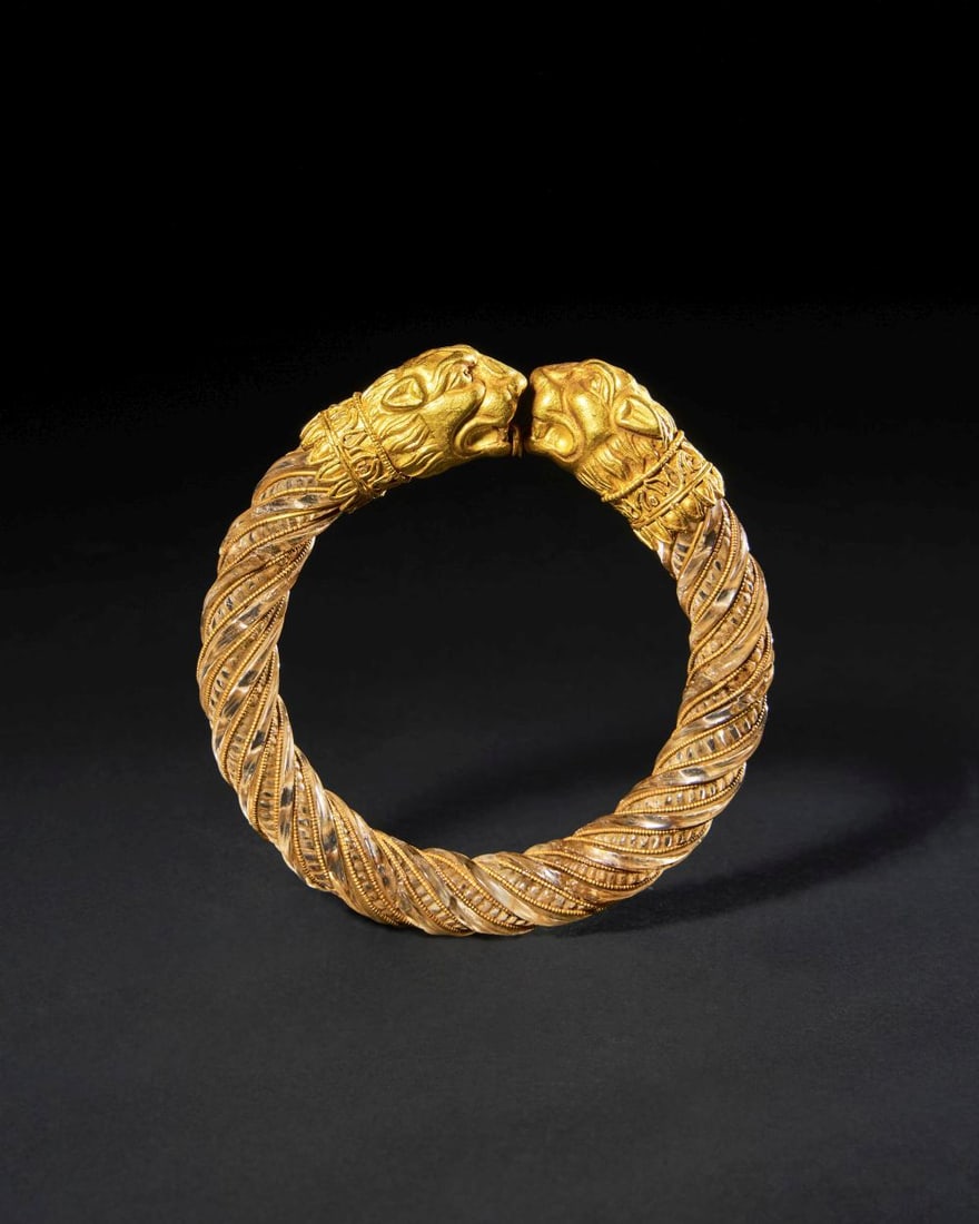 A GREEK GOLD "LION HEAD" TERMINAL & ROCK CRYSTAL BRACELET, CIRCA 500-350B.C. CLASSICAL PERIOD: A GREEK GOLD "LION HEAD" TERMINAL & ROCK CRYSTAL BRACELET, CIRCA 500-350B.C. CLASSICAL PERIOD This finely worked Greek bracelet combines a rock crystal hoop with elaborate gold decoration, creatin