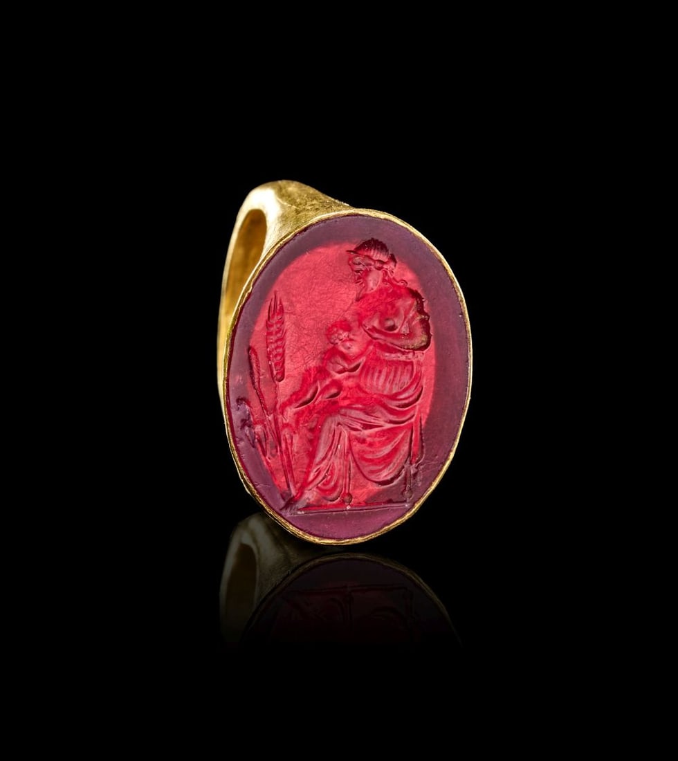 AN EXCEPTIONAL GREEK GOLD & AGATE INTAGLIO RING DEPICTING THE GODDESS DEMETER & BABY NURSING OVER WH: AN EXCEPTIONAL GREEK GOLD & AGATE INTAGLIO RING DEPICTING THE GODDESS DEMETER & BABY NURSING OVER WH This exceptional Greek gold ring is set with an oval red agate intaglio, finely engraved wi
