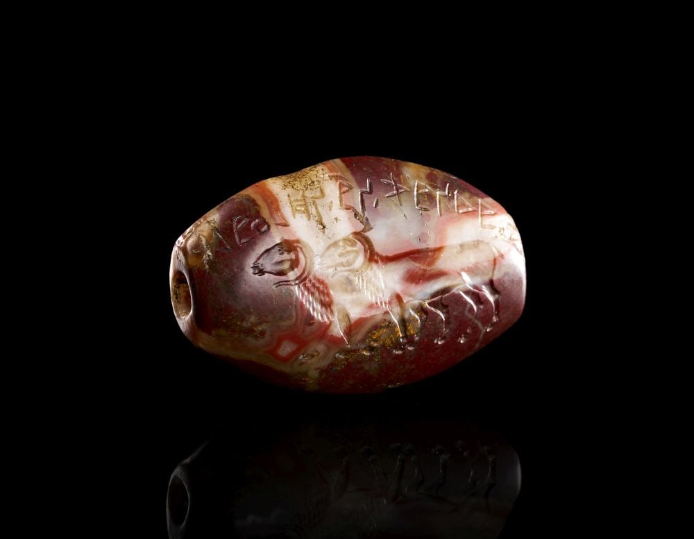 AN ACHAEMENID BANDED AGATE RAM STAMP SEAL, CIRCA 5TH-4TH CENTURY B.C.: AN ACHAEMENID BANDED AGATE RAM STAMP SEAL, CIRCA 5TH-4TH CENTURY B.C. Finely carved oval banded agate stamp seal engraved with two walking rams in profile, rendered with curved horns and textured flee