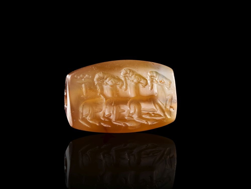 A GREEK THREE RAM AGATE STAMP SEAL, CLASSICAL PERIOD, CIRCA LATE 5TH CENTURY B.C.: A GREEK THREE RAM AGATE STAMP SEAL, CLASSICAL PERIOD, CIRCA LATE 5TH CENTURY B.C. A Greek agate stamp seal of warm orange-brown tone, carved with a finely detailed scene of three rams advancing in pro