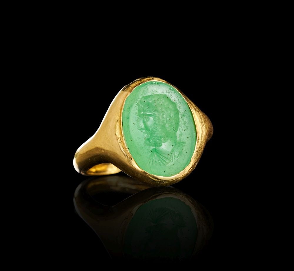 A ROMAN INTAGLIO GOLD RING DEPICTING A BEARDED MAN, CIRCA 1ST-2ND CENTURY A.D. PROBABLY EMERALD: A ROMAN INTAGLIO GOLD RING DEPICTING A BEARDED MAN, CIRCA 1ST-2ND CENTURY A.D. PROBABLY EMERALD A Roman gold ring set with an oval green intaglio, probably emerald, engraved with the bust of a bearded