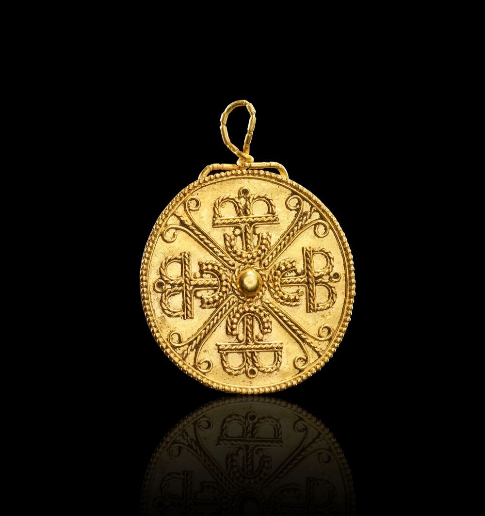 A BYZANTINE GOLD FILIGREE AMULET, CIRCA 11TH CENTURY: A BYZANTINE GOLD FILIGREE AMULET, CIRCA 11TH CENTURY A Byzantine gold filigree amulet of circular form, decorated on the front with an elaborate cross-based design composed of applied wirework, scroll
