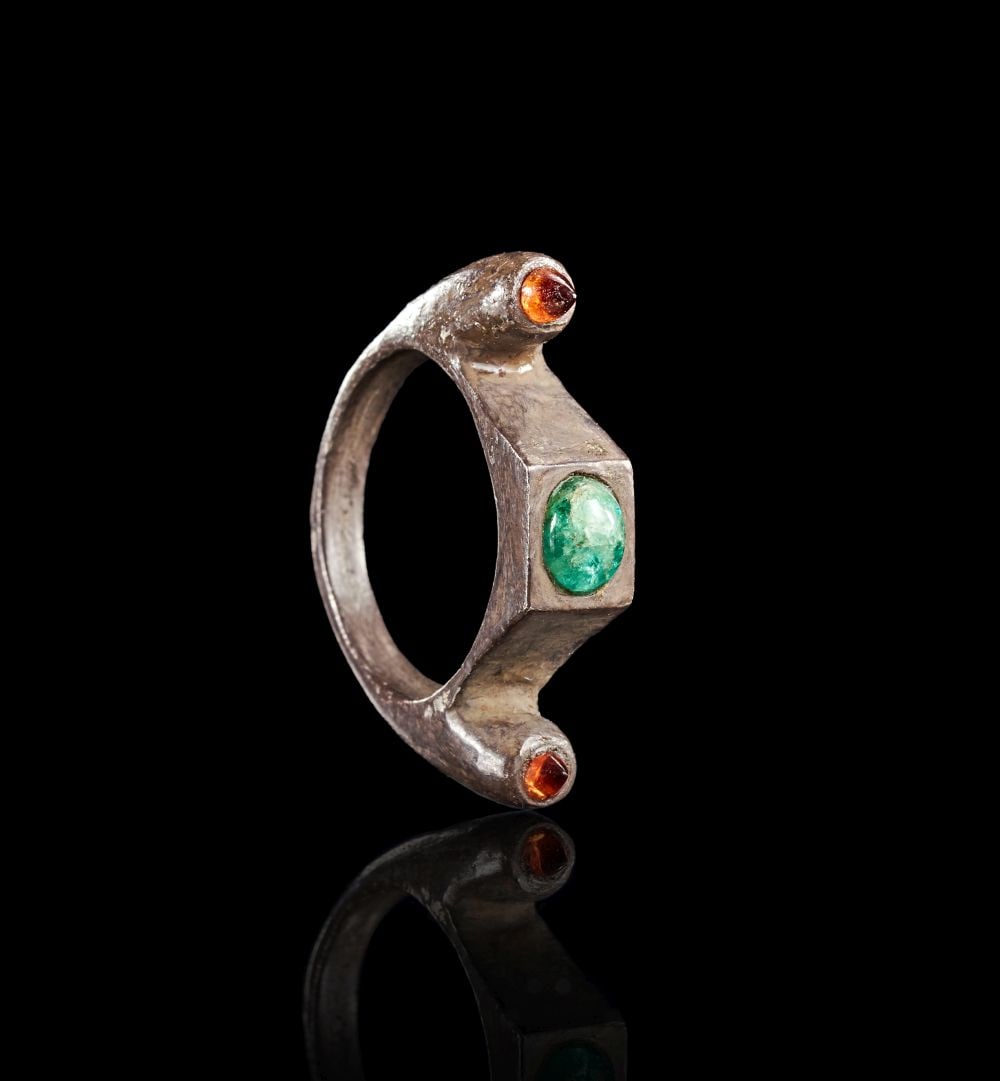 A LATE ROMAN OR EARLY BYZANTINE SILVER RING WITH EMERALDS & GARNETS, CIRCA 4TH-7TH CENTURY A.D.: A LATE ROMAN OR EARLY BYZANTINE SILVER RING WITH EMERALDS & GARNETS, CIRCA 4TH-7TH CENTURY A.D. A Late Roman or Early Byzantine silver ring with a heavy hoop and angular architectural bezel. The c