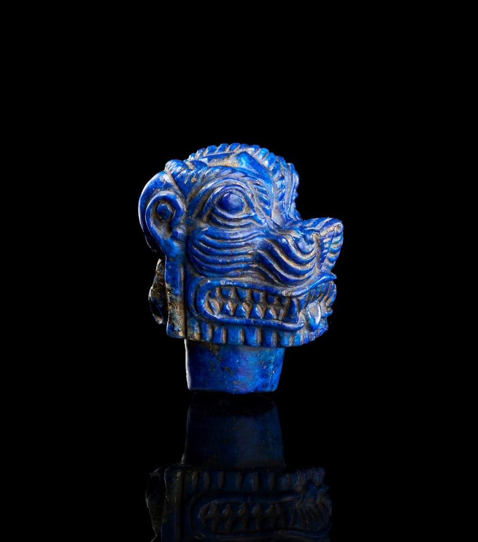 A NEO-ASSYRIAN LAPIS LAZULI HEAD OF PAZUZU CIRCA 8TH-7TH CENTURY B.C.: A NEO-ASSYRIAN LAPIS LAZULI HEAD OF PAZUZU, CIRCA 8TH–7TH CENTURY B.C. Carved from deep blue lapis lazuli, this small Neo-Assyrian head of Pazuzu presents the demon in a compact and forceful for