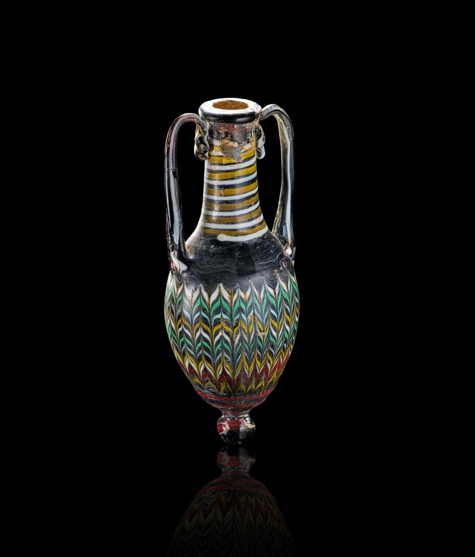 AN EASTERN MEDITERRANEAN CORE-FORMED GLASS AMPHORA CIRCA 2ND-MID 1ST CENTURY B.C.: AN EASTERN MEDITERRANEAN CORE-FORMED GLASS AMPHORA CIRCA 2ND-MID 1ST CENTURY B.C. Formed in dark glass with vivid trail decoration, this elegant amphora has an ovoid body, narrow cylindrical neck, eve
