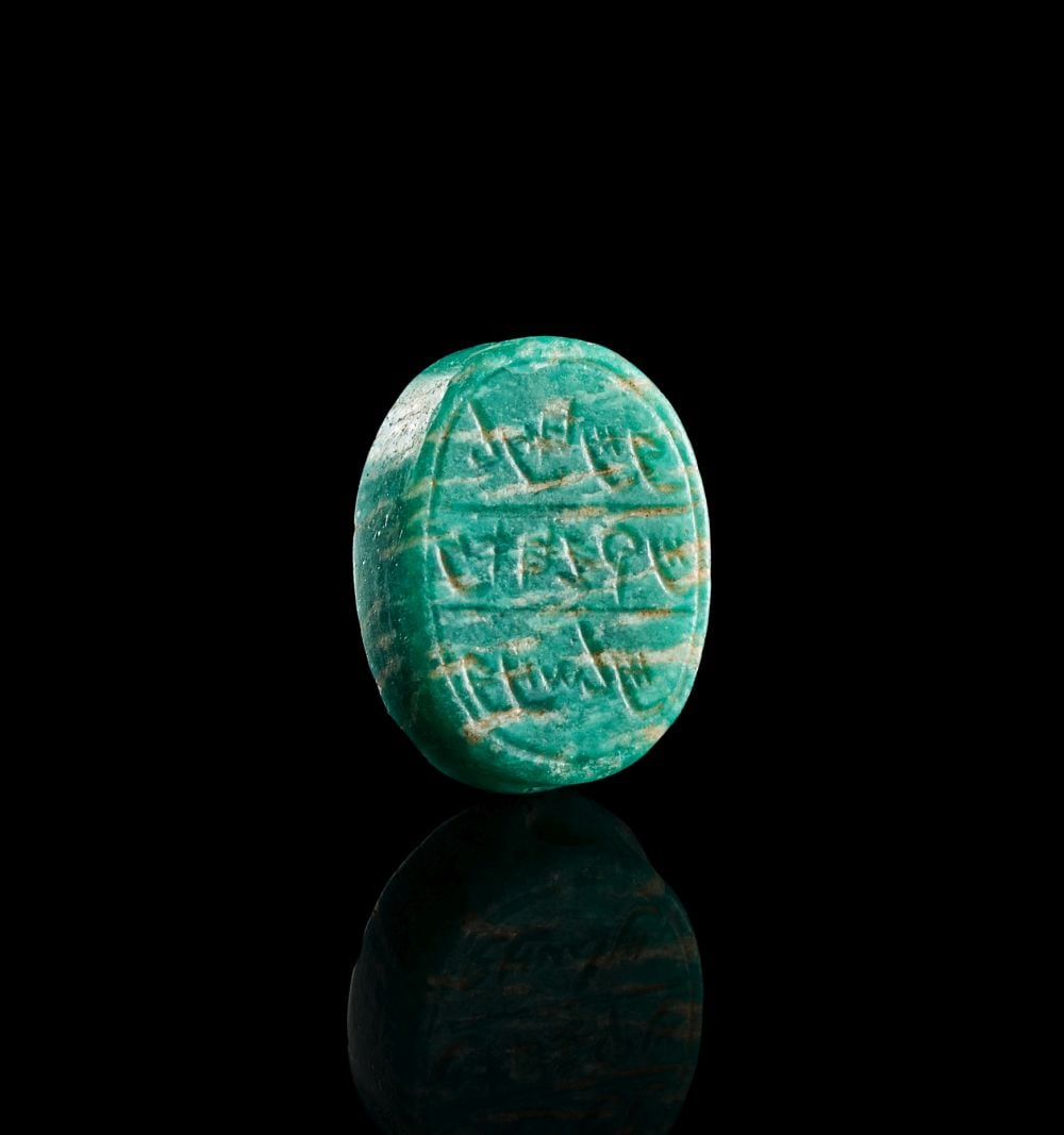 A PHOENICIAN INSCRIBED MOTTED GREEN & WHITE JASPER SCARAB CIRCA 5TH CENTURY B.C.: A PHOENICIAN INSCRIBED MOTTED GREEN & WHITE JASPER SCARAB CIRCA 5TH CENTURY B.C. Carved from mottled green and white jasper, the scarab has a compact oval form with a softly domed back and a flatt