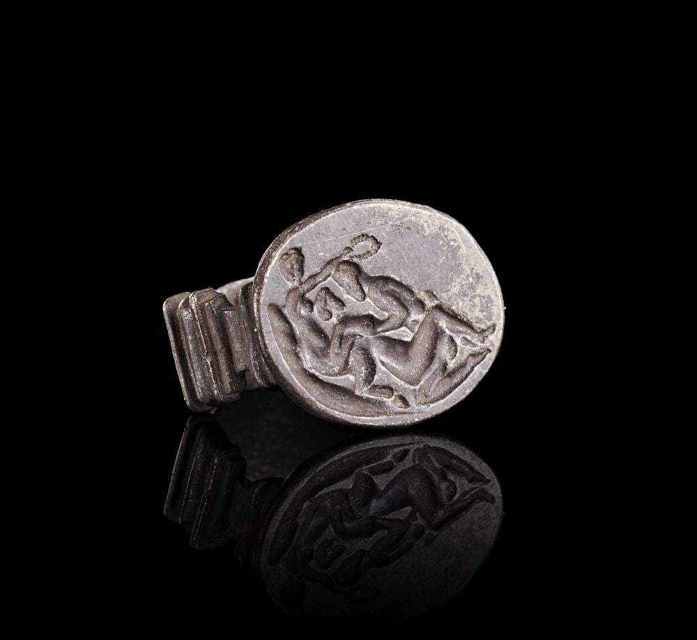 A ROMAN SOLID SILVER RING DEPICTING AN EROTIC SCENE, 2ND - 3RD CENTURY A.D.: A ROMAN SOLID SILVER RING DEPICTING AN EROTIC SCENE, 2ND - 3RD CENTURY A.D. A solid silver Roman ring with a broad hoop and an oval bezel engraved with an erotic scene. The ring is robustly formed, wi