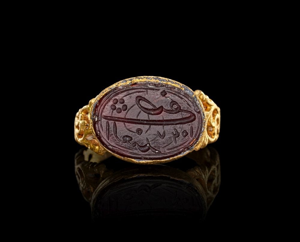 A CALLIGRAPHIC INSCRIBED SEAL, SET ON A GOLD MOUNT, SAFAVID, IRAN 17TH CENTURY: A CALLIGRAPHIC INSCRIBED SEAL, SET ON A GOLD MOUNT, SAFAVID, IRAN 17TH CENTURY Set on a gold mount, this Safavid seal ring is centred by an oval dark red stone engraved with a calligraphic inscription
