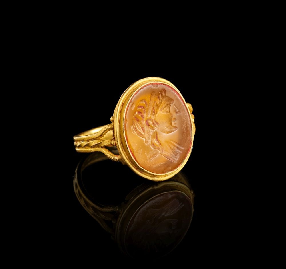 A GREEK GOLD RING DEPICTING AN ATHLETE, CIRCA 3RD CENTURY A.D.: A GREEK GOLD RING DEPICTING AN ATHLETE, CIRCA 3RD CENTURY A.D. Formed in gold, this ring is set with an oval agate intaglio engraved with the profile bust of an athlete. The hoop is slender and worked