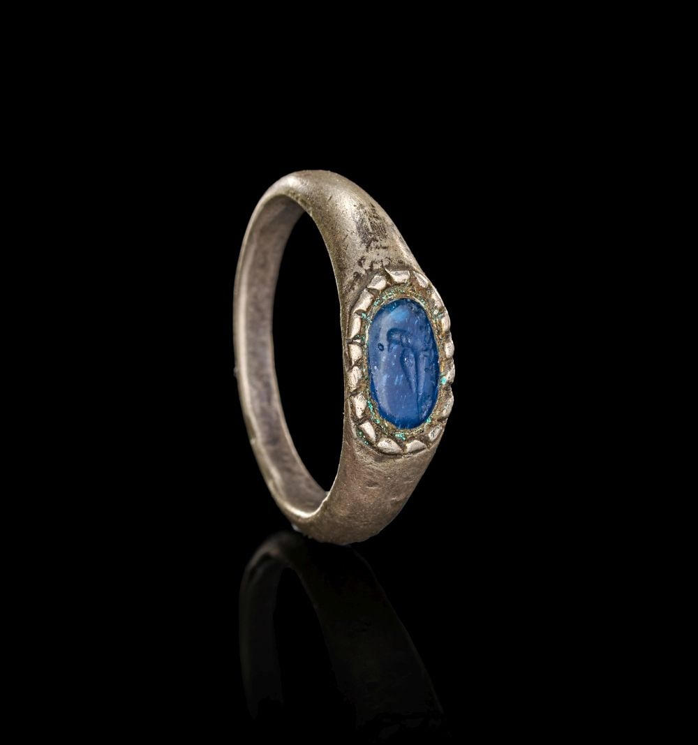 A MEDIEVAL SILVER RING WITH AN ENGRAVED BLUE GEM DEPICTING A BIRD, CIRCA 14TH CENTURY (1 of 4)