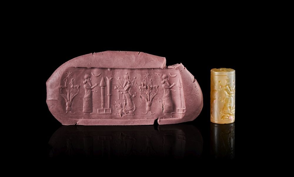 A NEO-BABYLONIAN AGATE CYLINDER SEAL CIRCA 1000-800 B.C.: A NEO-BABYLONIAN AGATE CYLINDER SEAL CIRCA 1000-800 B.C. Carved from pale honey-coloured agate, this Neo-Babylonian cylinder seal has a tall cylindrical form pierced longitudinally for suspension or m
