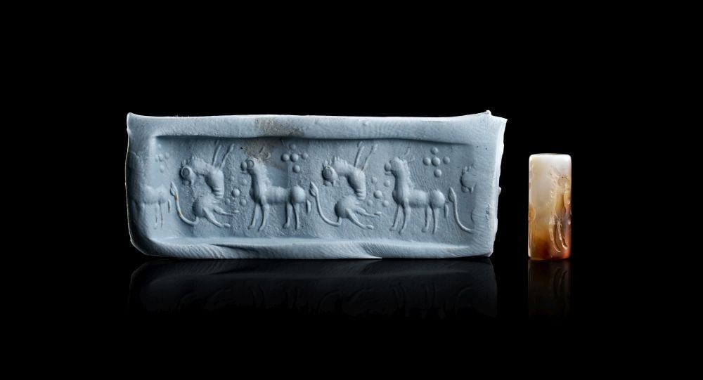 A NEO-BABYLONIAN BANDED AGATE CYLINDER SEAL CIRCA 1000-800 B.C.: A NEO-BABYLONIAN BANDED AGATE CYLINDER SEAL CIRCA 1000-800 B.C. Carved from banded agate, this Neo-Babylonian cylinder seal has a compact cylindrical form pierced longitudinally for suspension or moun