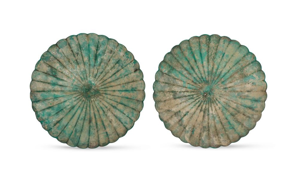 A PAIR OF KHORASAN BRONZE RIBBED DISHES, NORTH EAST IRAN, 12TH CENTURY: A PAIR OF KHORASAN BRONZE RIBBED DISHES, NORTH EAST IRAN, 12TH CENTURY Each dish of circular form, worked with a radiating ribbed design rising from a central boss and extending to a scalloped outer e