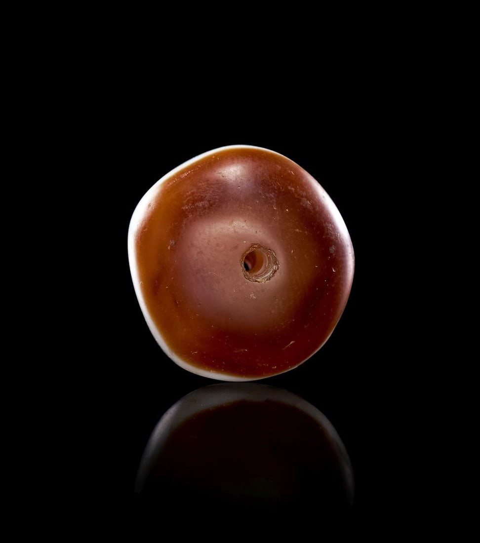 AN AGATE "DZI" EYE BEAD, 1ST-2ND CENTURY A.D. OR LATER: AN AGATE "DZI" EYE BEAD, 1ST-2ND CENTURY A.D. OR LATER Carved and polished from agate, this bead is of compact rounded form, its gently domed surfaces shaped to sit comfortably within the hand or agai