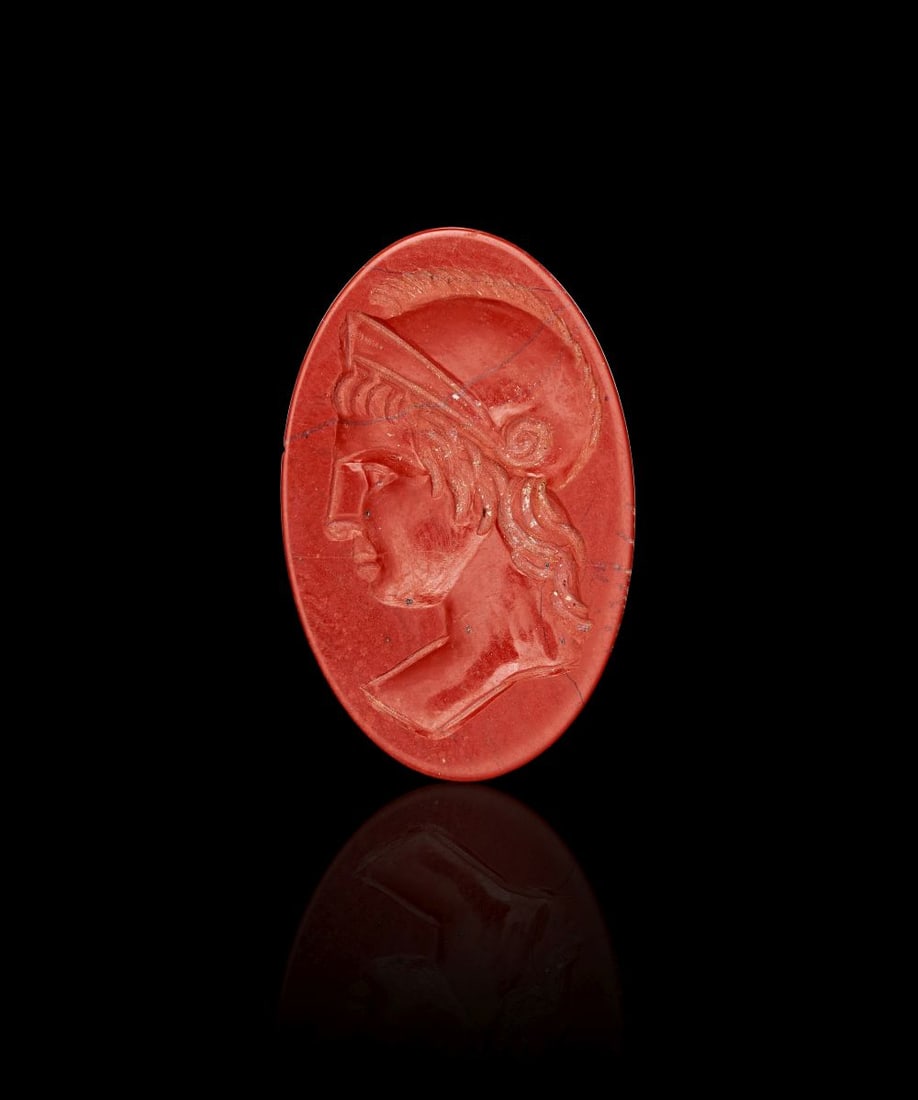 A ROMAN RED JASPER INTAGLIO DEPICTING A BUST OF MINERVA, 1ST-2ND CENTURY A.D.: A ROMAN RED JASPER INTAGLIO DEPICTING A BUST OF MINERVA, 1ST-2ND CENTURY A.D. Carved from red jasper, this oval intaglio depicts the bust of Minerva in left profile. The goddess is shown wearing a cre