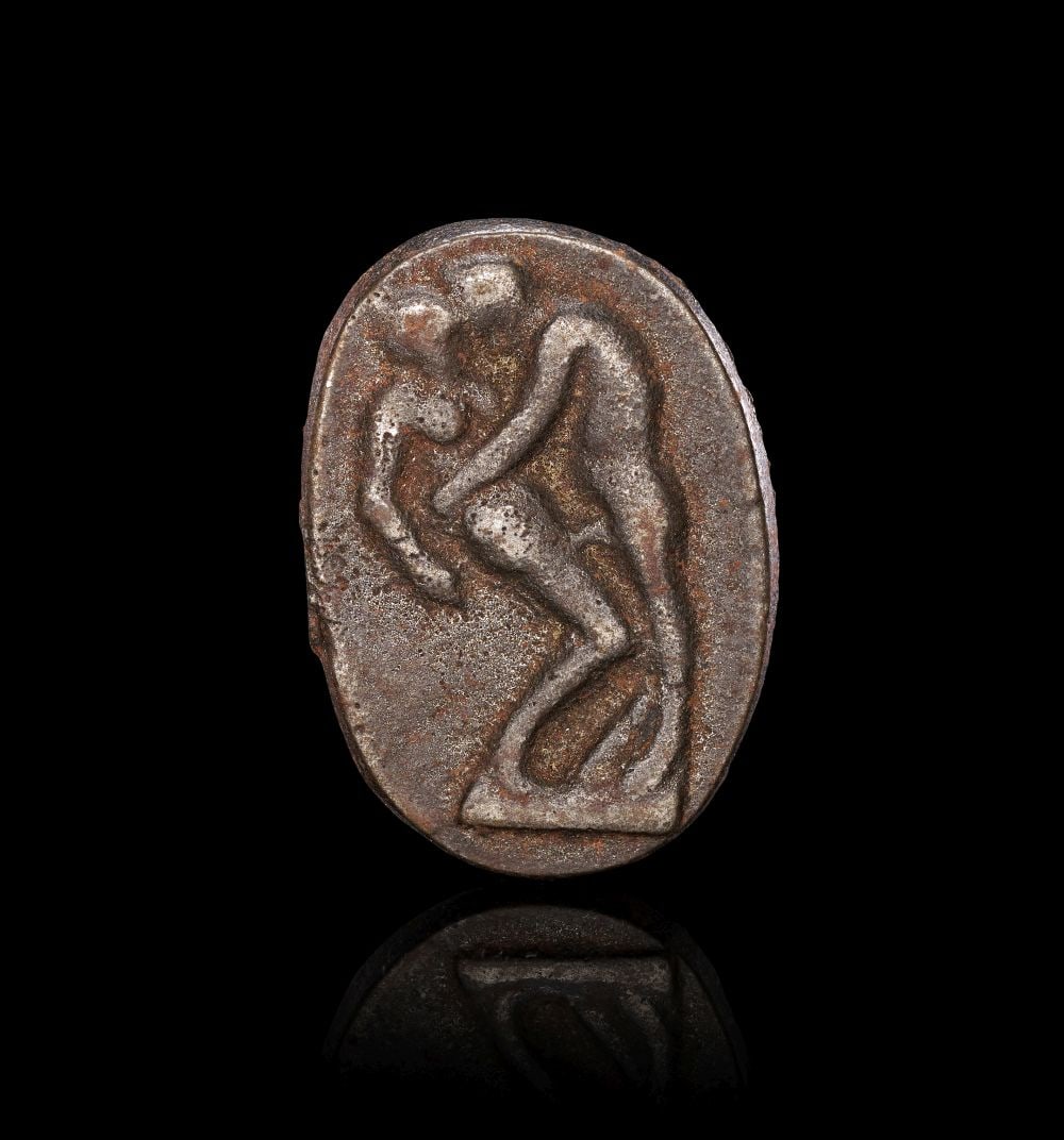 AN EASTERN GREEK EROTIC SOLID SILVER PLAQUE, CIRCA 1ST CENTURY B.C. OR LATER: AN EASTERN GREEK EROTIC SOLID SILVER PLAQUE, CIRCA 1ST CENTURY B.C. OR LATER Cast in solid silver, this small plaque is of rounded rectangular form, its arched upper edge enclosing a raised erotic sce