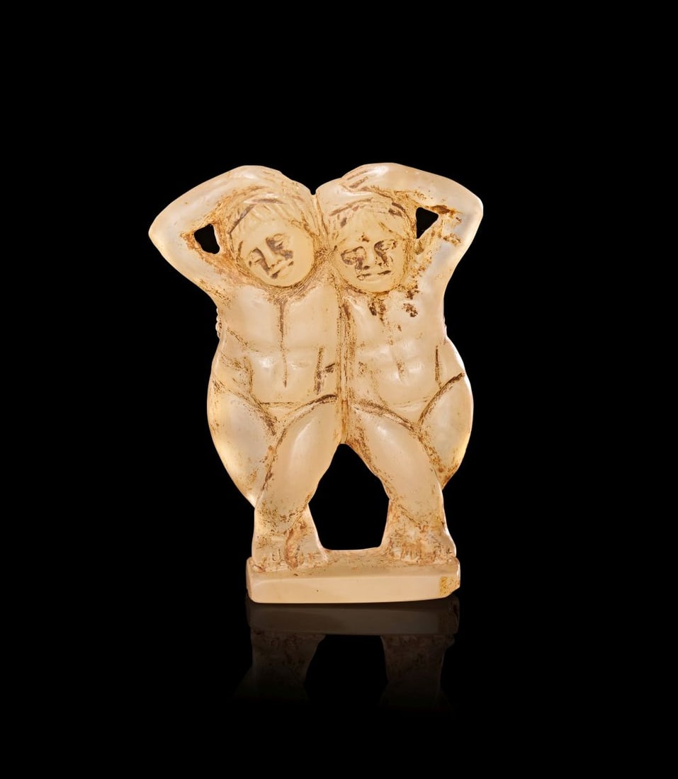 AN EASTERN GREEK CHALCEDONY GROUP OF TWO NAKED DANCING FEMALES, 3RD CENTURY B.C.: AN EASTERN GREEK CHALCEDONY GROUP OF TWO NAKED DANCING FEMALES, 3RD CENTURY B.C. Carved in pale honey-coloured chalcedony, this small sculptural group depicts two nude female figures standing side by 